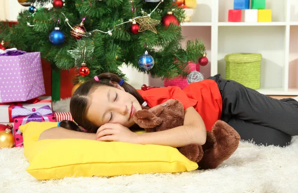 Маленькая девочка спит возле рождественской елки — стоковое фото