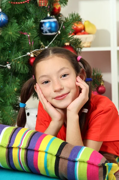 Kleines Mädchen träumt in der Nähe des Weihnachtsbaums — Stockfoto