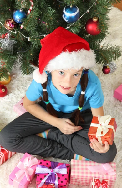 Hediye kutusu Noel ağacının yakınında tutan küçük bir kız — Stok fotoğraf