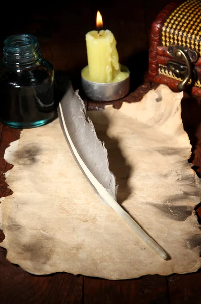 Papel viejo con pluma de tinta cerca de la vela de iluminación en la mesa de madera —  Fotos de Stock