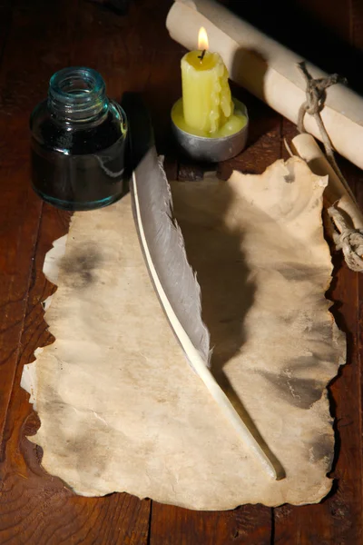 Papel viejo con pluma de tinta cerca de la vela de iluminación en la mesa de madera — Foto de Stock