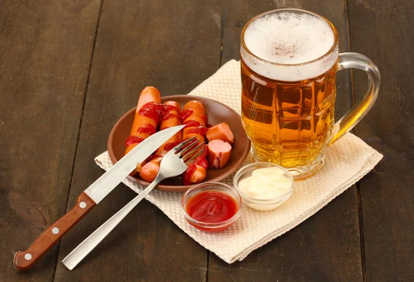 Cerveza y embutidos a la parrilla sobre fondo de madera —  Fotos de Stock