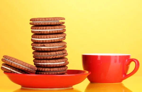 Schokoladenkekse mit cremiger Schicht auf rotem Teller gelber Hintergrund — Stockfoto