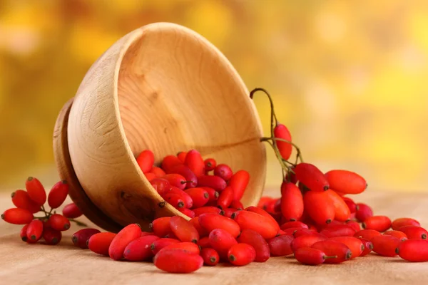 Barberries maduras em tigela de madeira, na mesa, no fundo amarelo — Fotografia de Stock