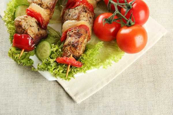 Tasty grilled meat and vegetables on skewer on plate, on table — Stock Photo, Image