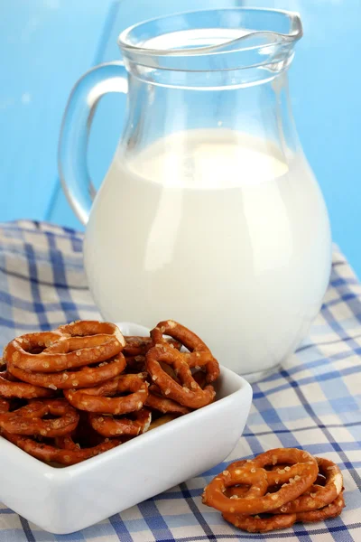 Tasty pretzels in white bowl and milk jug on wooden table close-up — Stock fotografie
