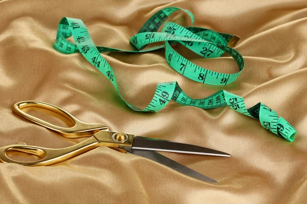 Металлические ножницы на золотой ткани — стоковое фото