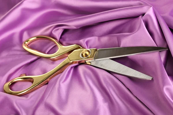 Metal scissors on purple fabric — Stock Photo, Image