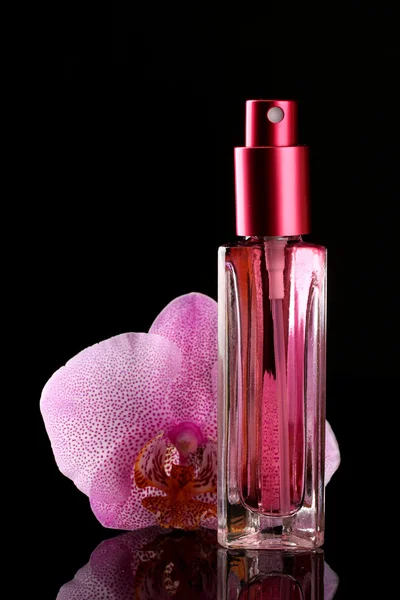 Frauenparfüm in schöner Flasche und Orchideenblume, auf schwarzem Hintergrund — Stockfoto