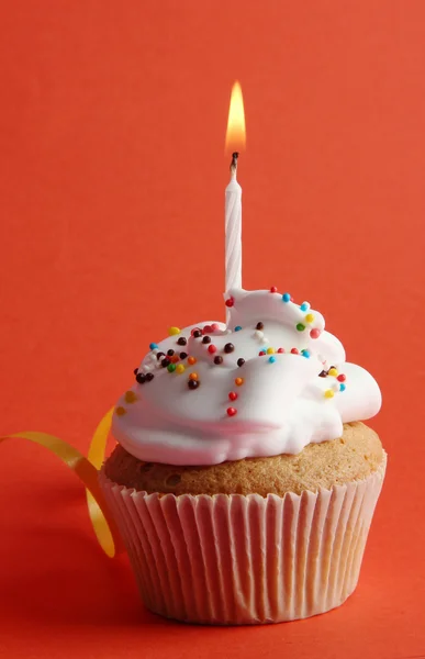 Tasty birthday cupcake with candle, on red background — Stock Photo, Image