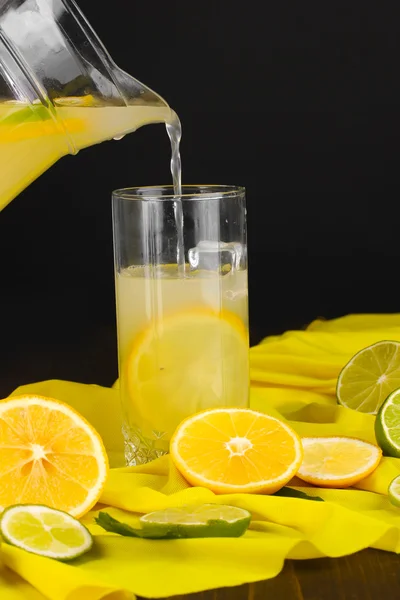 Citrus saft i glas och tillbringare med citrus runt på gult tyg på träbord närbild — Stockfoto