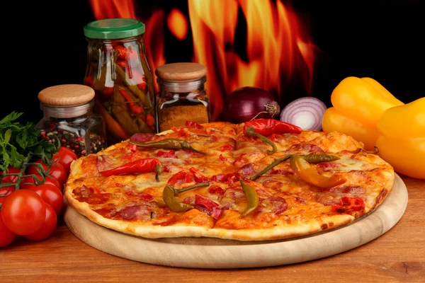 Leckere Pfefferoni-Pizza mit Gemüse auf Holzbrett auf Flammenhintergrund — Stockfoto