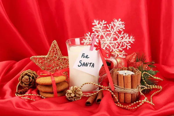 Biscotti per Santa: Immagine concettuale di biscotti allo zenzero, latte e decorazione natalizia su sfondo rosso — Foto Stock