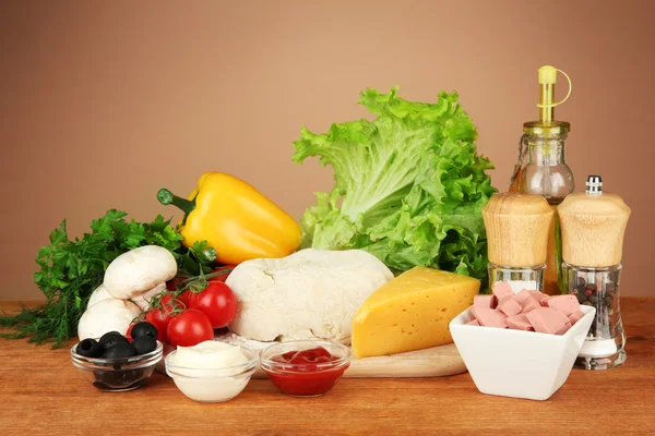 Ingredients for pizza on wooden table on brown background — Stock Photo, Image