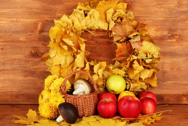 Herbstliche Komposition mit gelben Blättern, Äpfeln und Pilzen auf hölzernem Hintergrund — Stockfoto