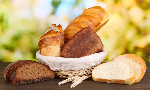 Pan fresco en canasta sobre mesa de madera sobre fondo natural — Foto de Stock