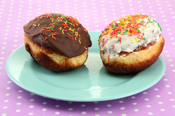 Leckere Donuts auf Farbteller auf Farbhintergrund — Stockfoto