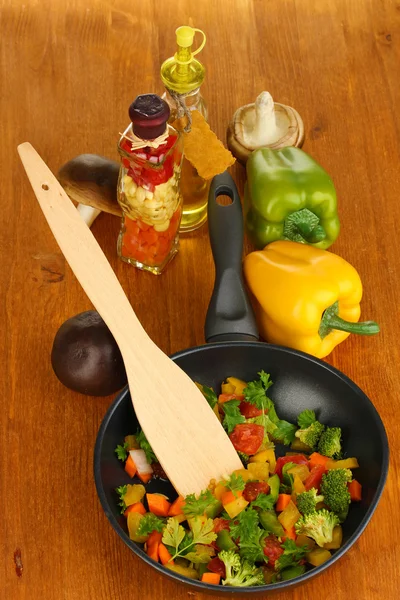 Verdure fresche affettate in padella con spezie e ingredienti su tavola di legno — Foto Stock
