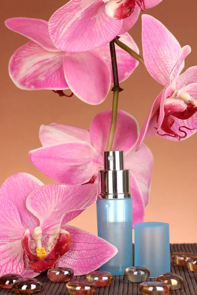 Frauenparfüm in schöner Flasche mit Orchideen auf braunem Hintergrund — Stockfoto