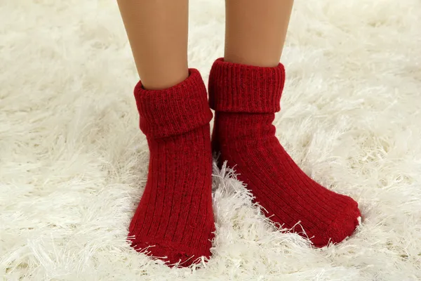 Frauenbeine in bunten Socken auf weißem Teppich-Hintergrund — Stockfoto