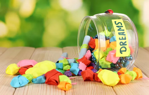 Glass vase with paper stars with dreams on wooden table on natural background — Stock Photo, Image