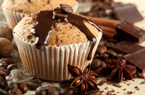 Tasty muffin cakes with chocolate, spices and coffee seeds, close up — Zdjęcie stockowe