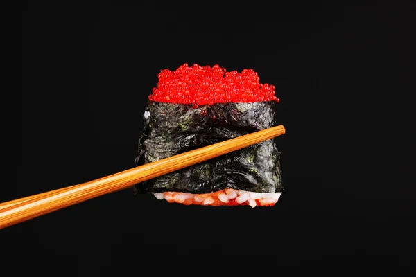 Tenendo sushi con bacchette isolate su nero — Foto Stock