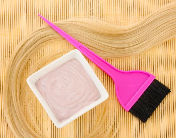 Tinte para el cabello en un tazón y cepillo para la coloración del cabello en la estera de bambú beige, primer plano — Foto de Stock