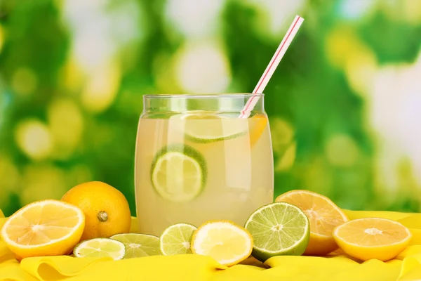 Limonada cítrica en banco de cristal de cítricos alrededor en tela amarilla sobre fondo natural — Foto de Stock