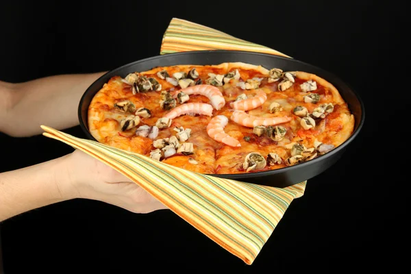 Mãos segurando pizza com frutos do mar isolados em preto — Fotografia de Stock