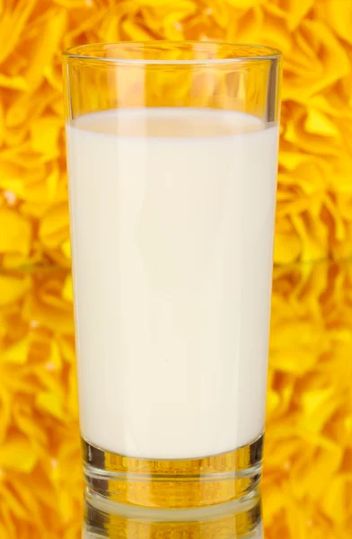 Glass of fresh new milk on decorative yellow background with reflection