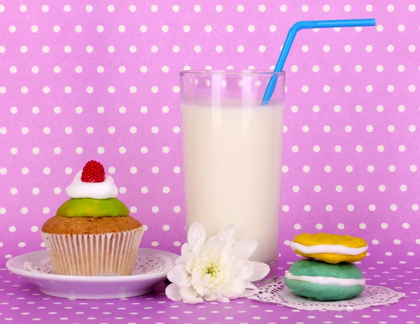 Glass of fresh new milk with confectionery on purple polka dot background — Stock Photo, Image