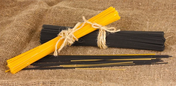Schwarze und gelbe Spaghetti auf Sacktuch Hintergrund — Stockfoto
