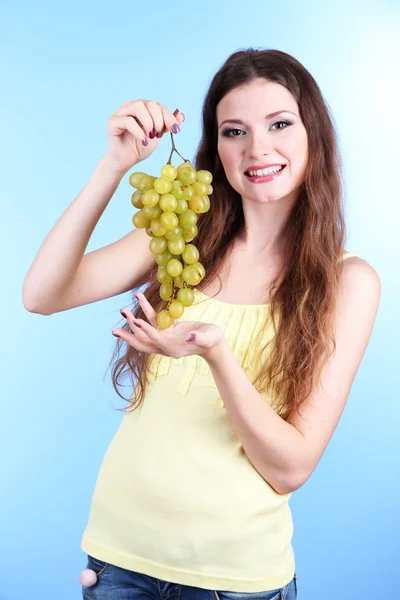 Bella donna con uva su sfondo blu — Foto Stock