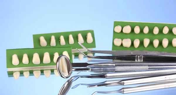 Set di strumenti dentali con dentiera su sfondo blu — Foto Stock
