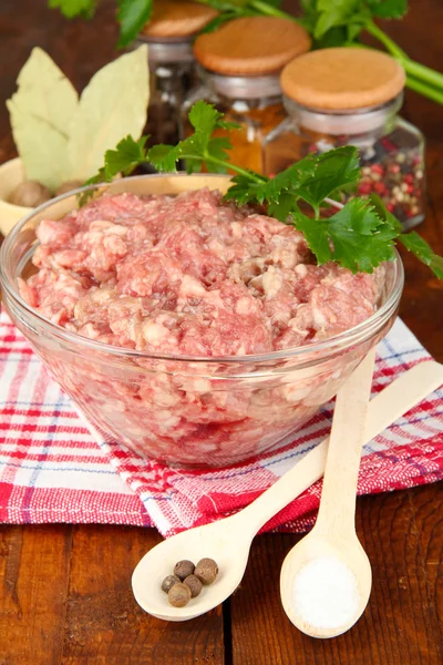 Bowl of raw ground meat with spices on wooden table Stock Picture