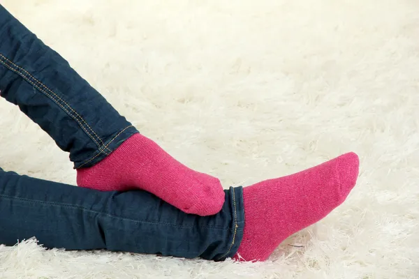 Patas femeninas en calcetines de colores sobre fondo de alfombra blanca — Foto de Stock