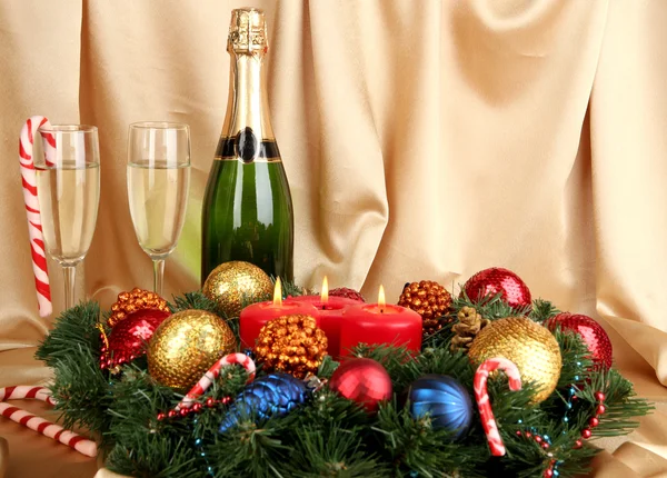Beautiful Christmas wreath in composition with champagne on gold fabric background — Stock Photo, Image