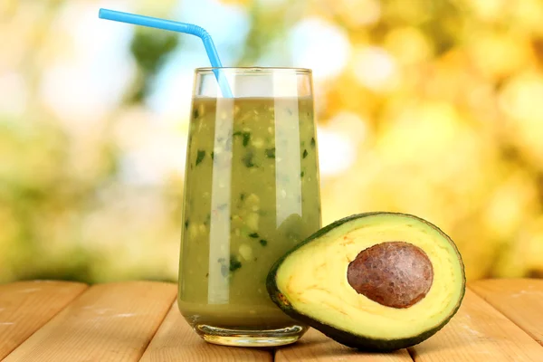 Useful fresh avocado and half avocado on wooden table on natural background — Stock Photo, Image