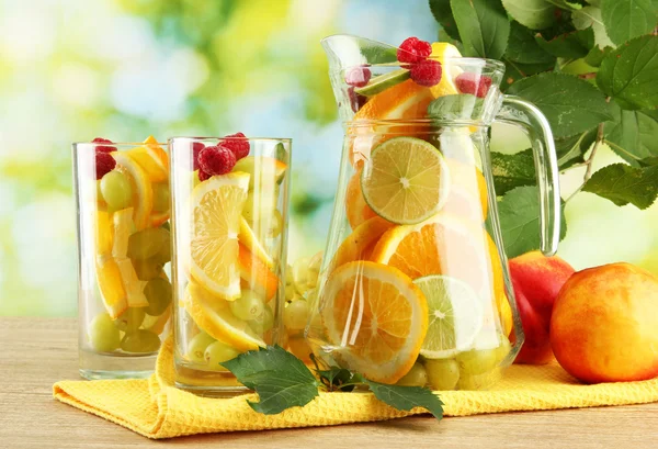 Burk och glas med citrusfrukter och hallon på grön bakgrund — Stockfoto