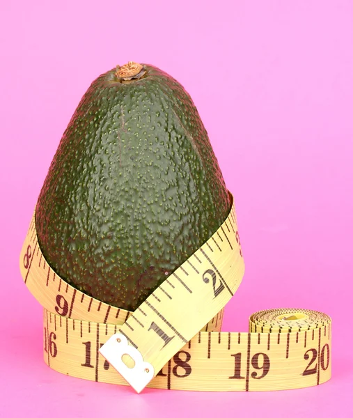 Avocado con metro su fondo rosa — Foto Stock