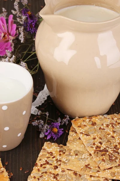 Kanna och kopp mjölk med cookies på träbord närbild — Stockfoto