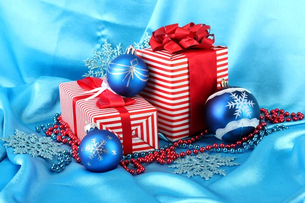 Colorful red gifts with blue Christmas balls, snowflakes and beads on blue background — Stockfoto