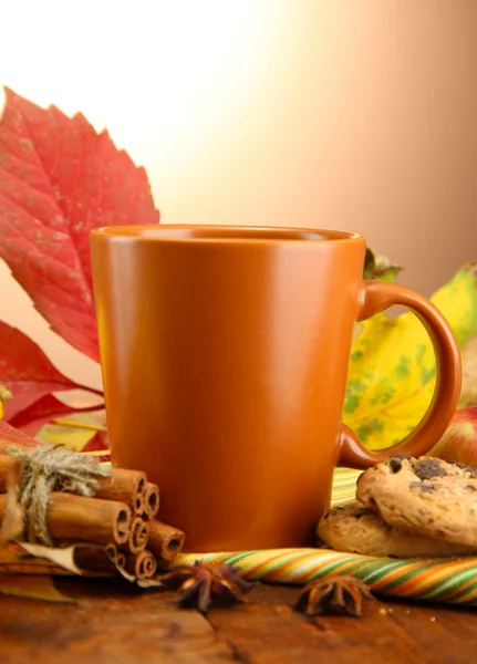 Tazza di tè caldo e foglie autunnali, su sfondo marrone — Foto Stock