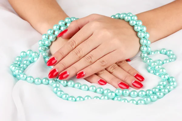 Female hands holding beads on color background — Stock Photo, Image