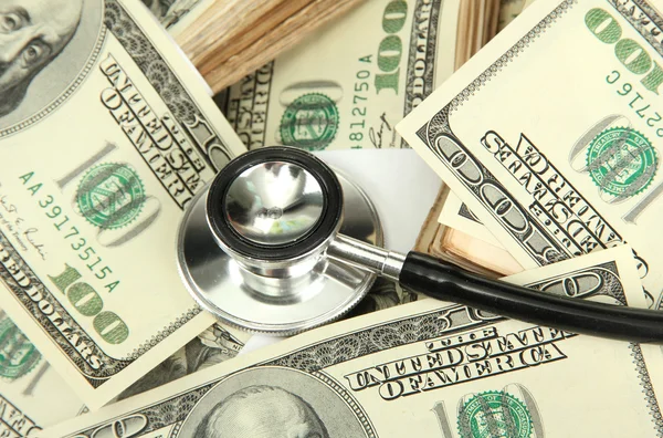 Концепция затрат на здравоохранение: стетоскоп и долларовый фон — стоковое фото