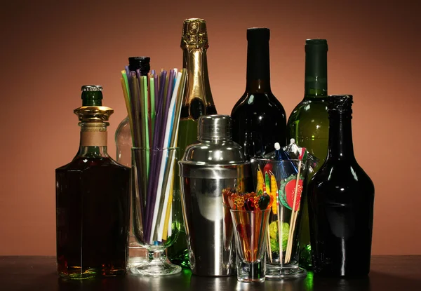 Collection of drinks, cocktail shaker and other bartender equipment on color background — Stock Photo, Image