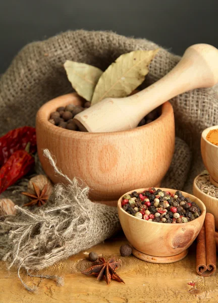 Mortar, bowls and spoons with spices, on table on grey background — Stock Photo, Image