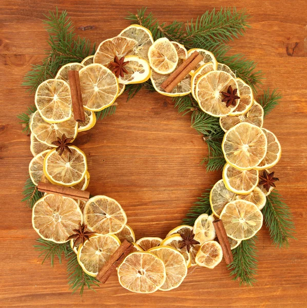 Weihnachtskranz aus getrockneten Zitronen mit Tanne auf Holzgrund — Stockfoto