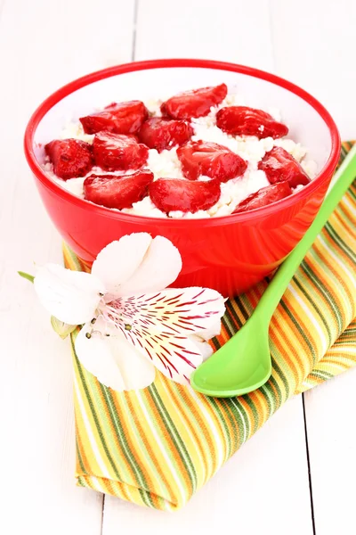 Cottage cheese in red bowl with sliced strawberries on white wooden table — Stock Photo, Image